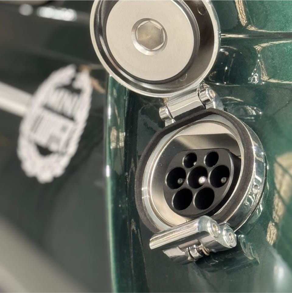 Type 2 charging socket on the green Mini, sitting behind the original fuel-filler flap.