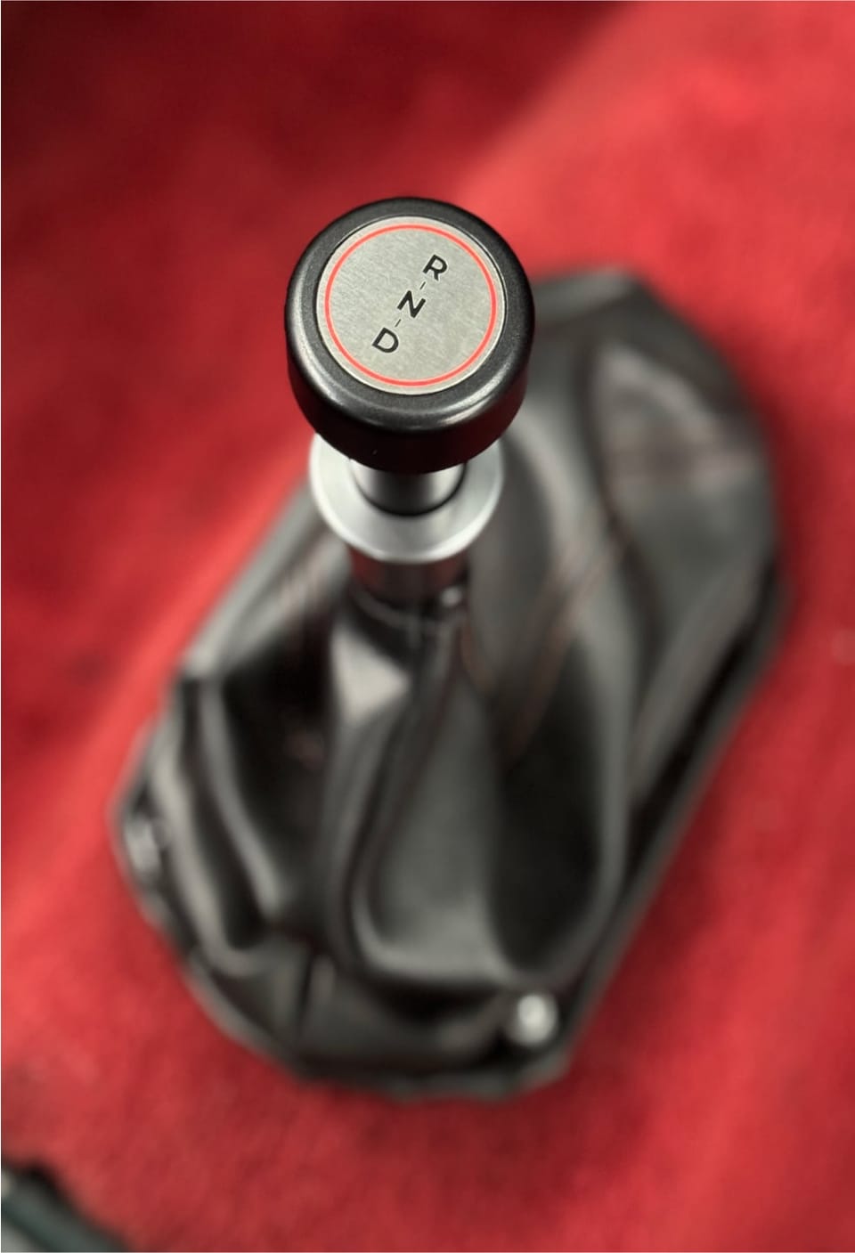 Brushed-metal drive selector plate with a D, N, R knob and black gaiter in the red Mini's cabin.