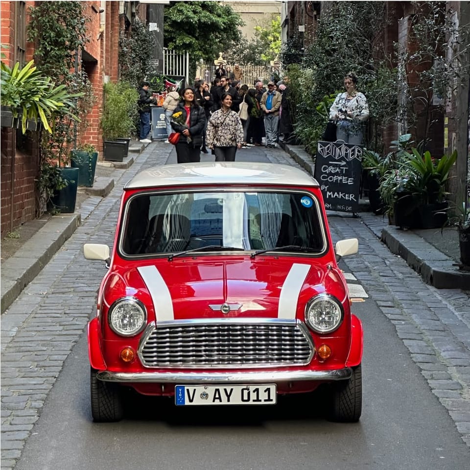 Red Classic Mini with a white roof and racing stripe, parked front-on in a Melbourne laneway.