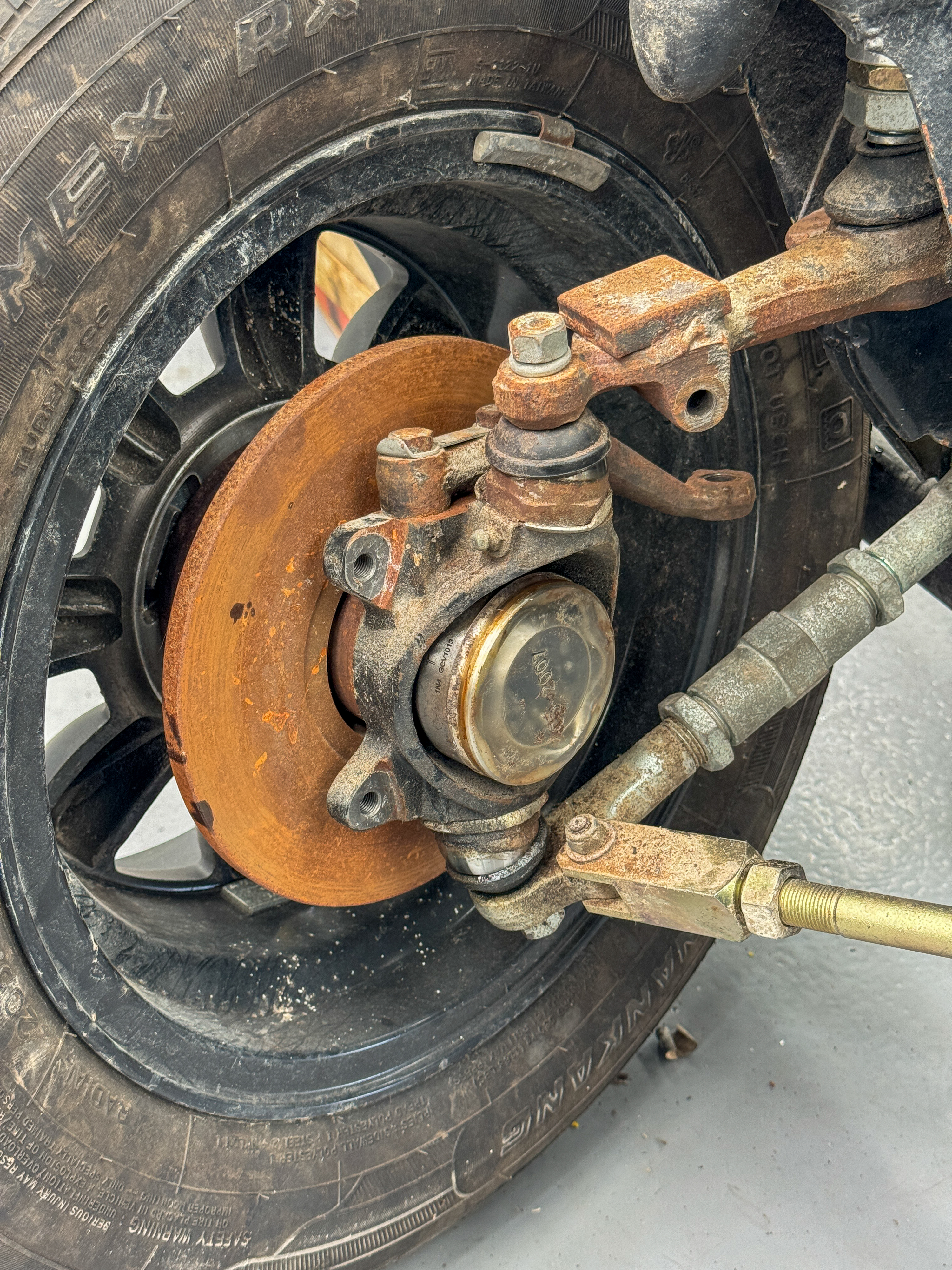 Original brake disc and caliper showing heavy surface rust and wear, photographed as part of the pre-build assessment.