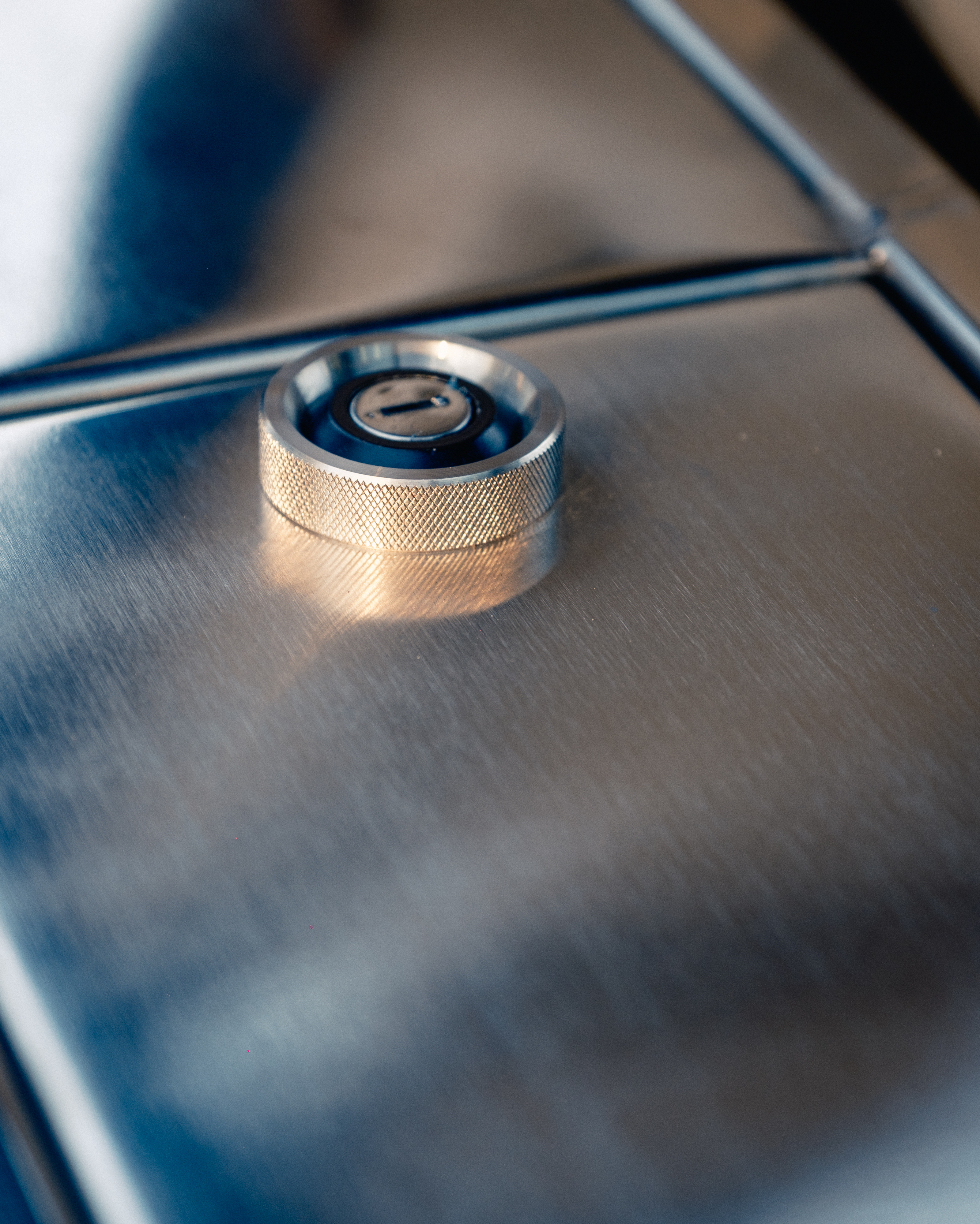 Extreme macro of the knurled stainless ignition barrel set flush into the body panel, catching directional light across its machined texture.