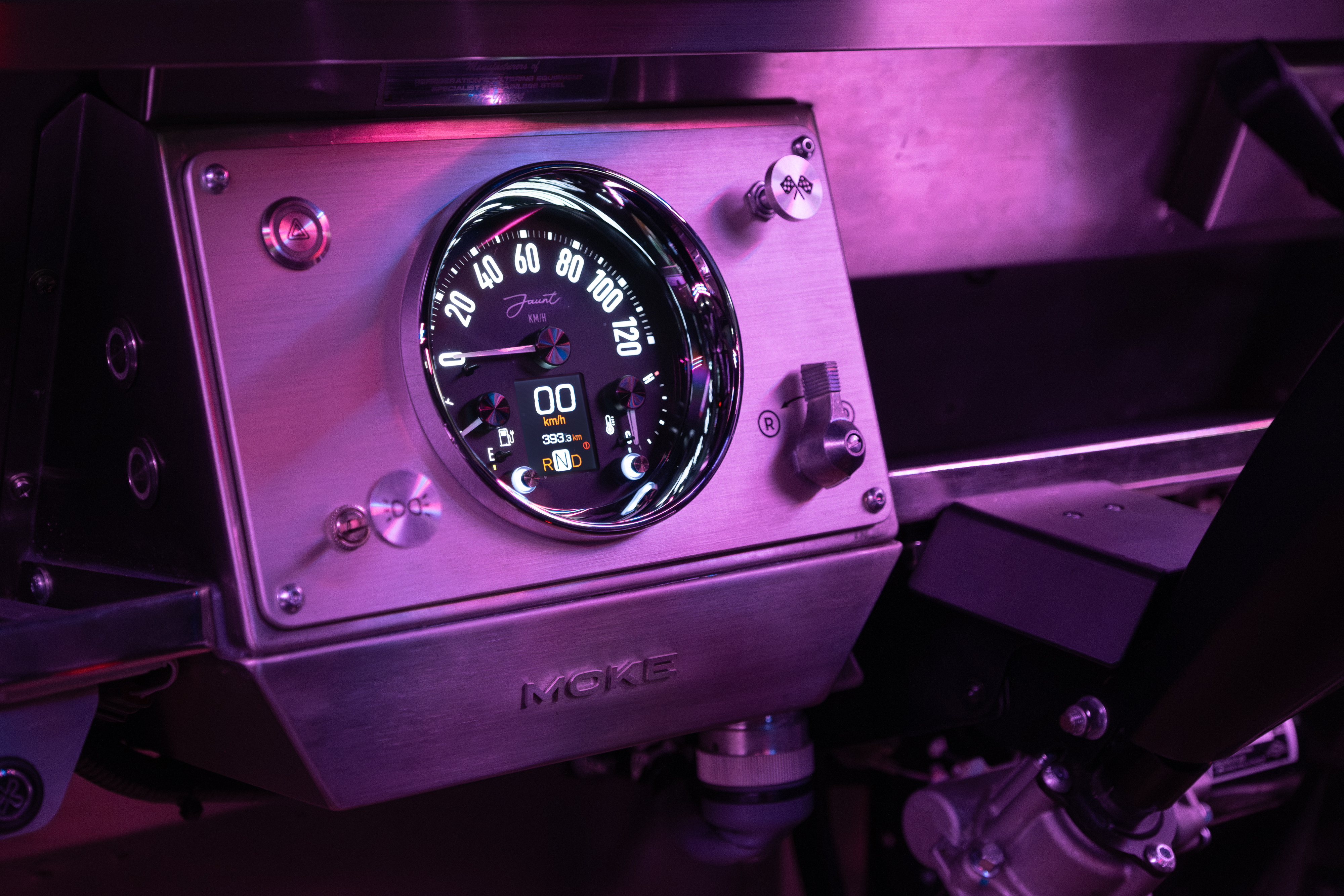 The brushed stainless dashboard with the Jaunt speedometer cluster lit up under pink ambient neon, the digital display showing RND and 393km odometer.